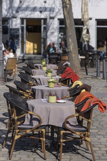 Tables and chairs with blankets in the outdoor area of a cafe