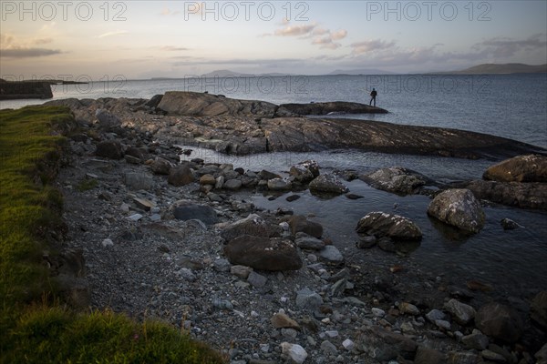 Man fishing off Renvyle harbour on summers evening along the Wild Atlantic way. Renvyle