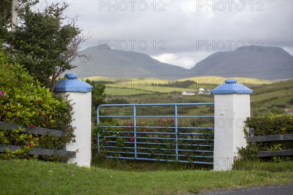 Entrance gate with white and blur piers against a mountain background in Sligo