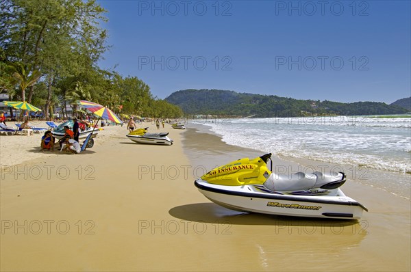 Patong Beach with umbrellas and tourists by the sea in Thailand