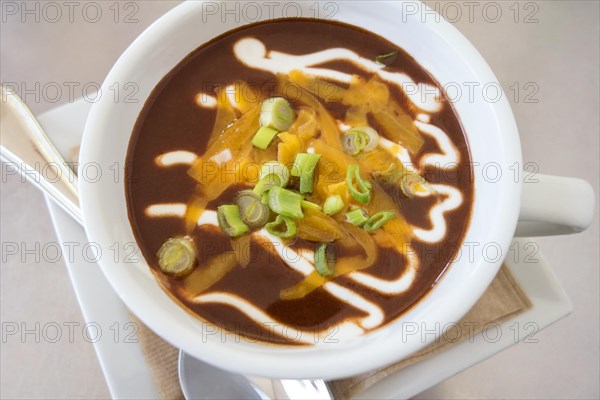 Creamy black bean soup with melted cheese and green onions