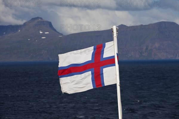 Flag of the Faroe Islands in front of the North Atlantic Ocean