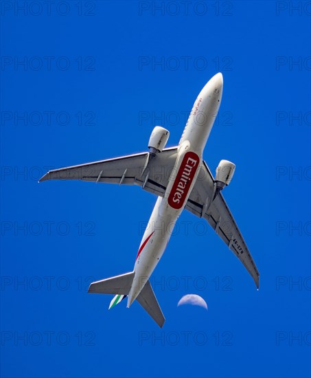 Ein Flugzeug Boeing 777-F1H der Fluggesellschaft Emirates beim Landeanflug auf den Frankfurter Flughafen vor dem Mond