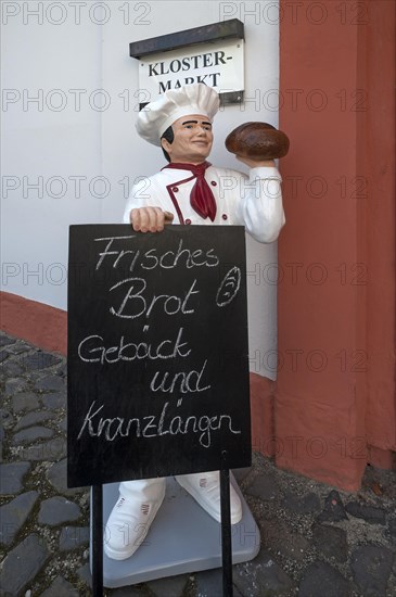 Baker's figure with offer board in front of the convent shop