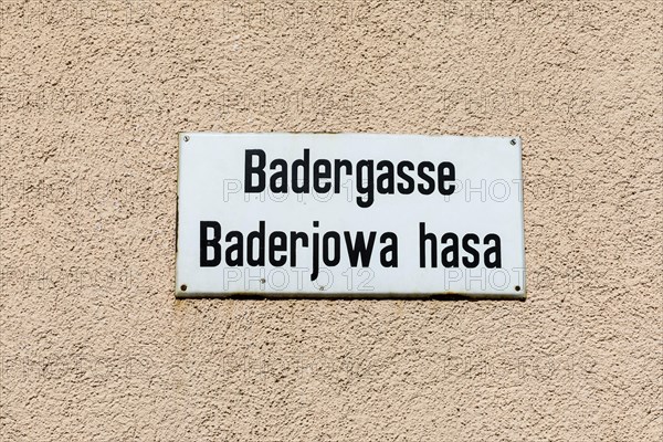 Bilingual alleyway sign of the Badergasse on a house wall
