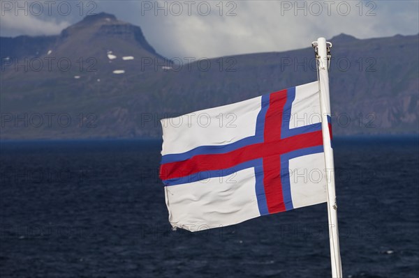 Flag of the Faroe Islands in front of the North Atlantic Ocean