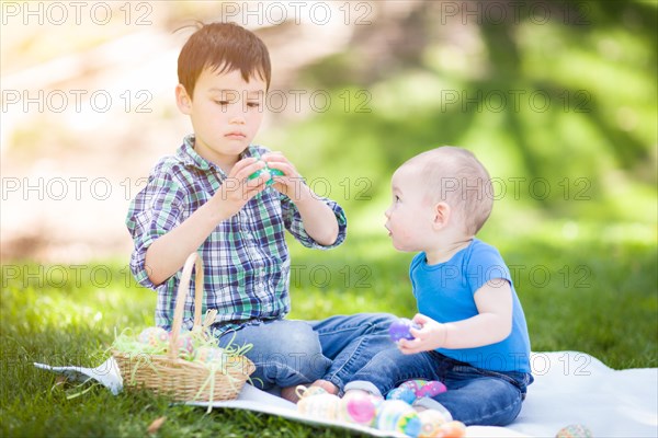 mixed-race chinese and caucasian boys outside in park playing with easter eggs