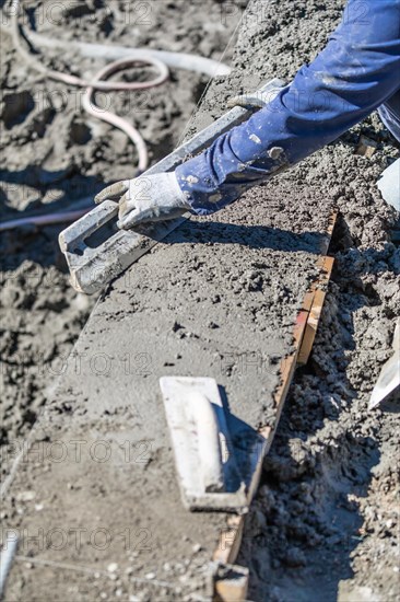 Pool construction worker working with A smoother rod on wet concrete
