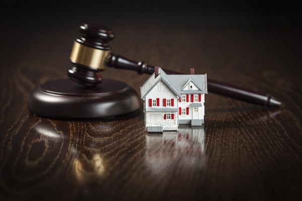 Gavel and small model house on wooden table