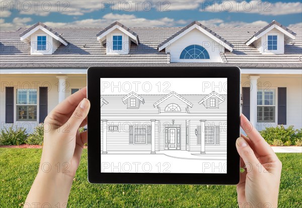 Female hands holding computer tablet with house drawing on screen