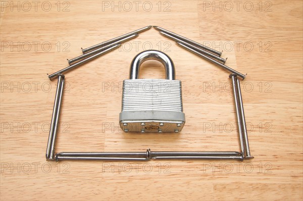 House of nails with lock on a wood background