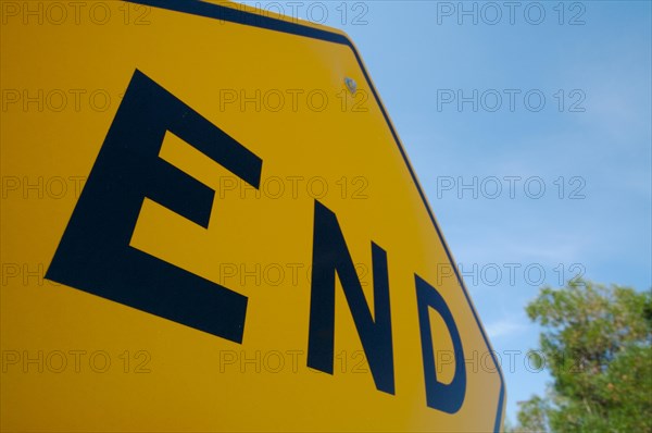 Yellow end sign with trees and blue sky