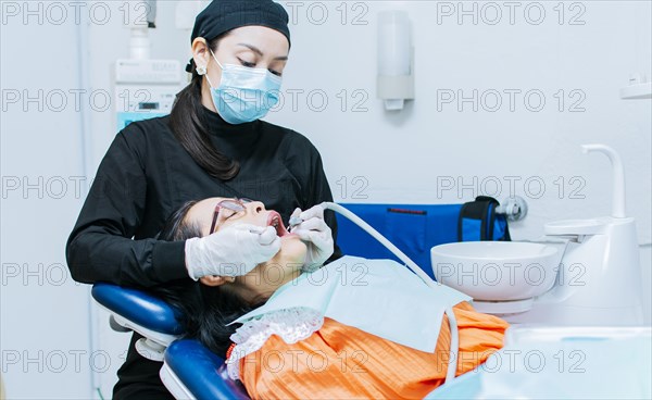 The stomatologist cleaning a patient's teeth