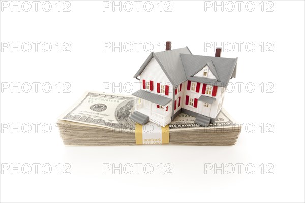Small house on stack of hundred dollar bills isolated on a white background