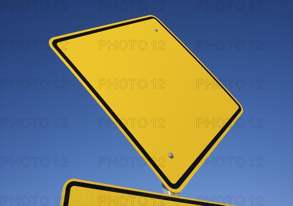 Blank yellow road sign against a deep blue sky with clipping path