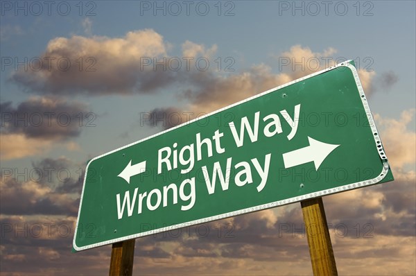Right and wrong way green road sign with dramatic blue sky and clouds