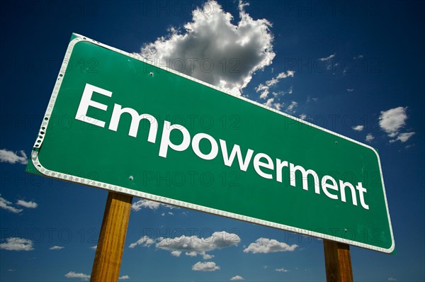 Empowerment green road sign over dramatic clouds and sky