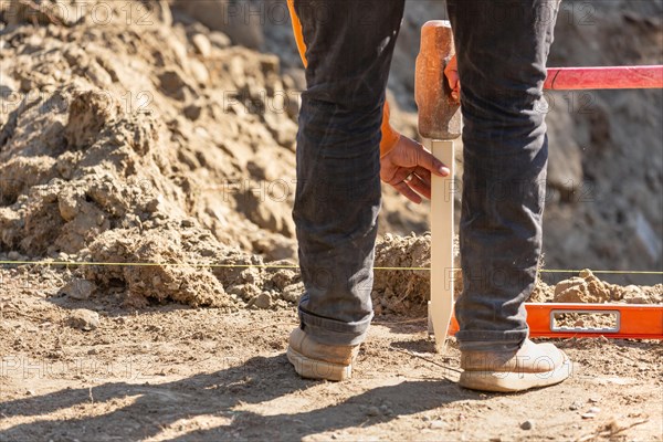 Worker installing stakes and lumber guides at construction site