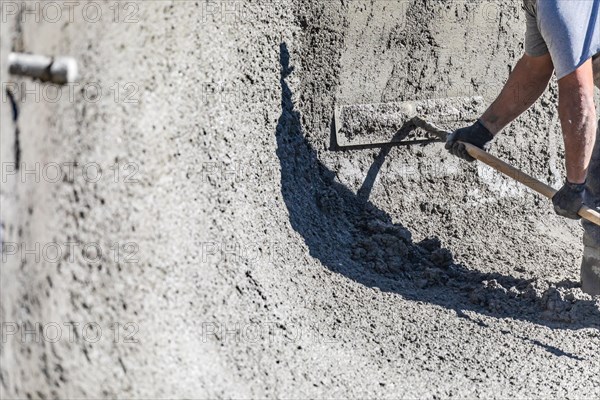 Pool construction worker working with A bullfloat on wet concrete