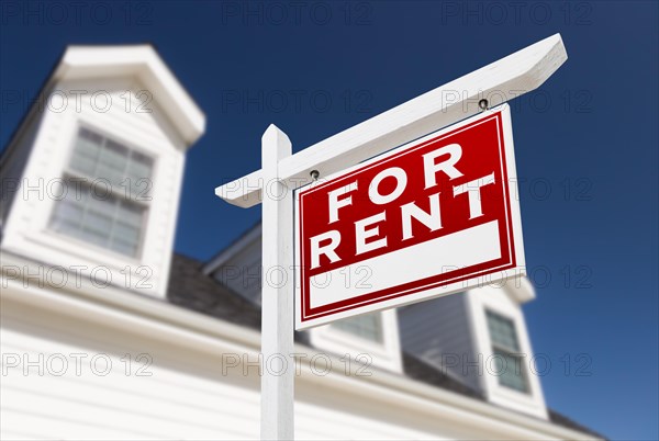 Right facing for rent real estate sign in front of house and deep blue sky