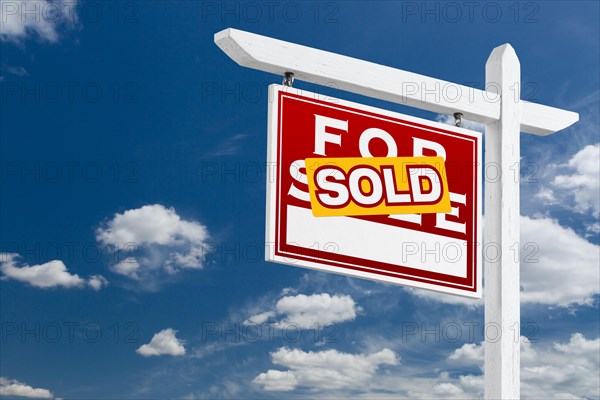 Left facing sold for sale real estate sign over blue sky and clouds with room for your text
