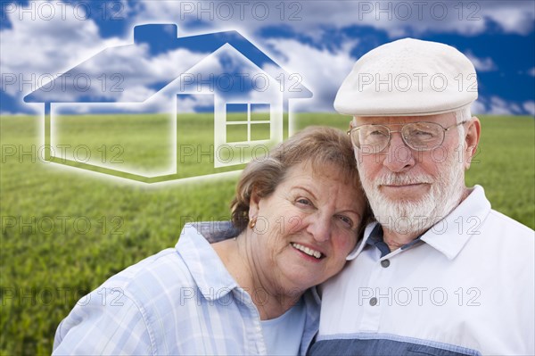 Loving senior couple standing in grass field with ghosted house on the horizon