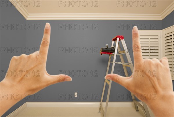 Hands framing grey painted room wall interior with ladder