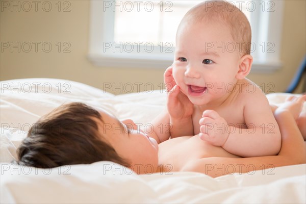 Young mixed-race chinese and caucasian baby brothers having fun on their blanket