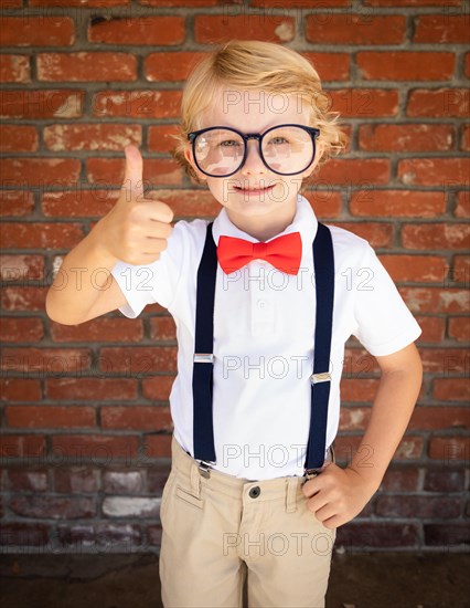 Cute young caucasian boy with thumbs up wearing glasses and red