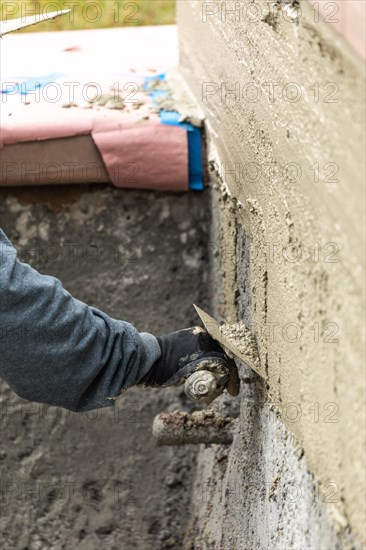 Tile worker applying cement with trowel at pool construction site