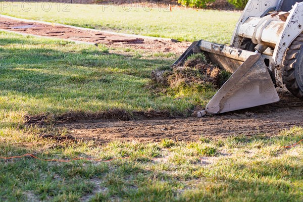 Small bulldozer removing grass from yard preparing for pool installation