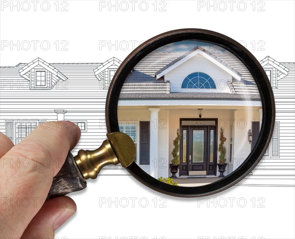 Hand holding magnifying glass revealing finished house build over drawing