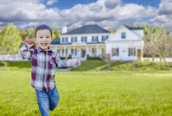 Cute happy mixed-race boy playing ball in his front yard