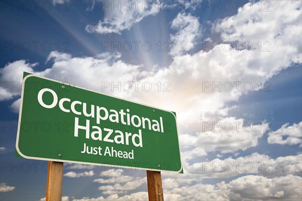 Occupational hazard green road sign with dramatic clouds and sky