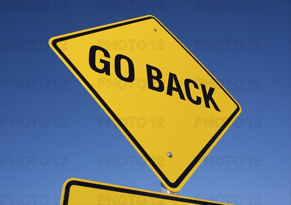 Go back yellow road sign against a deep blue sky with clipping path