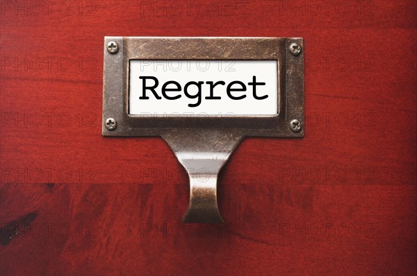 Lustrous wooden cabinet with regret file label in dramatic light