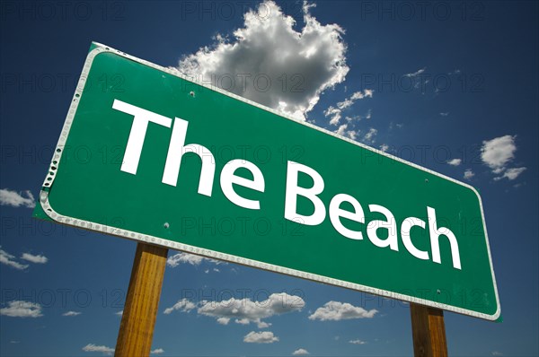 The beach green road sign with dramatic clouds and sky