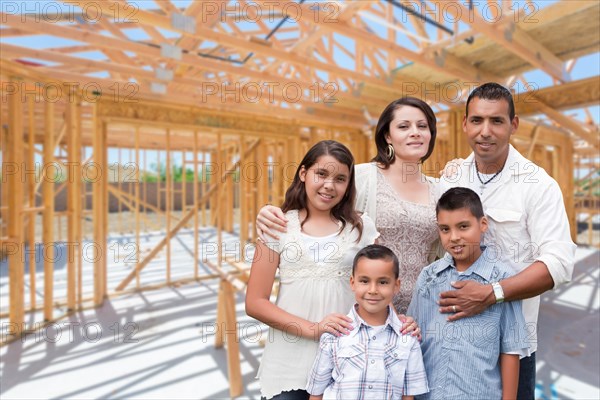 Young hispanic family on site inside new home construction framing