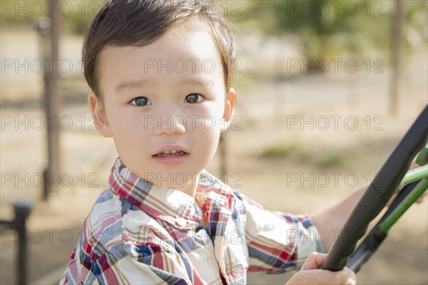 Adorable mixed-race young boy playing on the tractor at the pumpkin patch