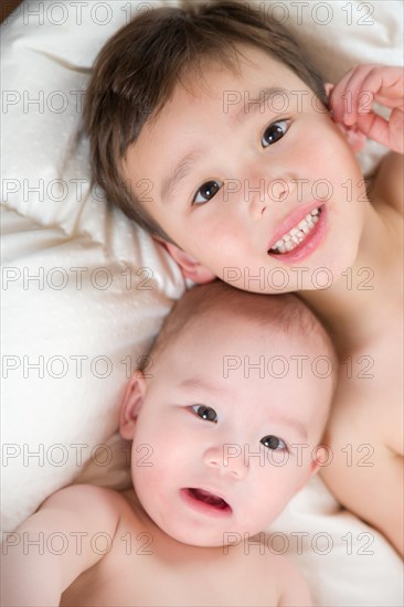 Young mixed-race chinese and caucasian baby brothers having fun on their blanket