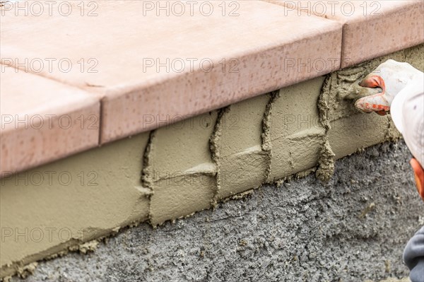 Tile worker applying cement with trowel at pool construction site