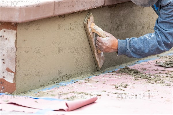 Worker smoothing cement with wooden float at construction site