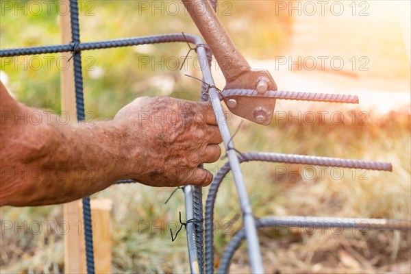 Worker using tools to bend steel rebar at construction site