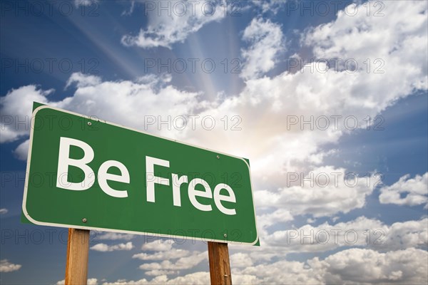 Be free green road sign with dramatic clouds and sky