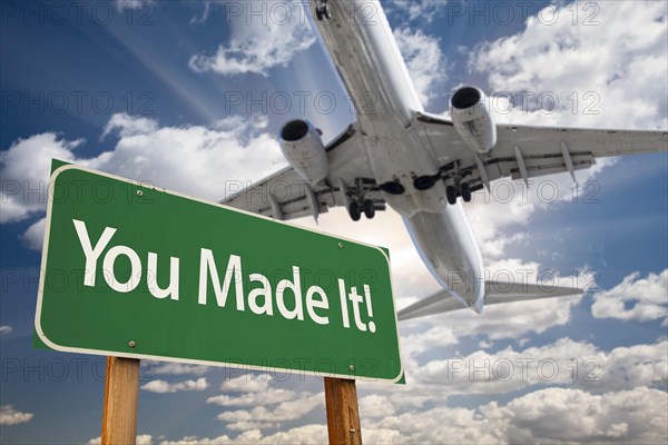 You made it green road sign and airplane above with dramatic blue sky and clouds