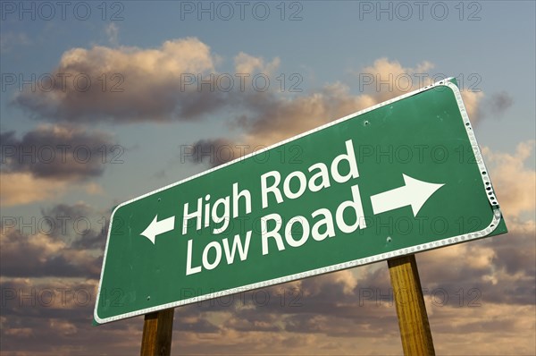 High and low road green road sign with dramatic blue sky and clouds