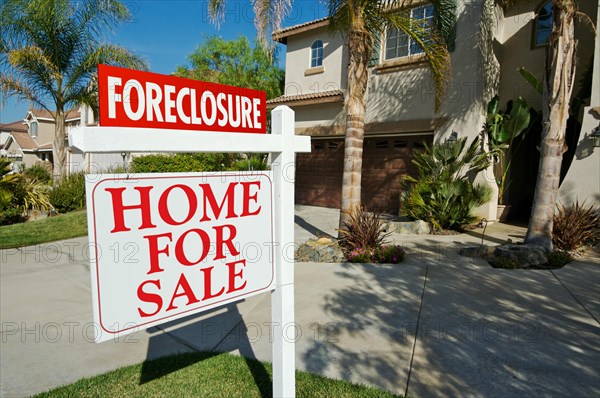 Foreclosure for sale real estate sign in front of beautiful new home