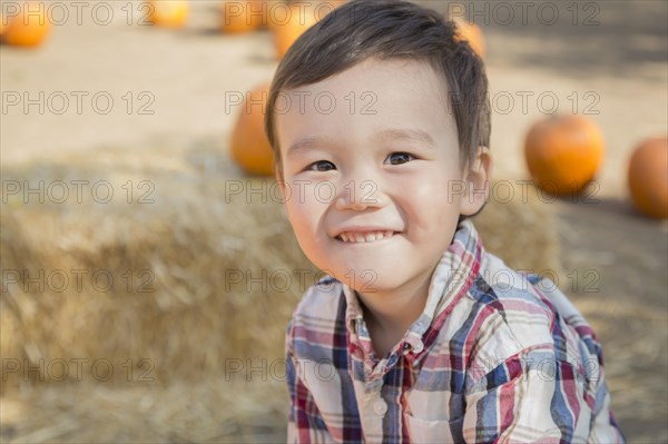 Cute mixed-race young boy having fun at the pumpkin patch