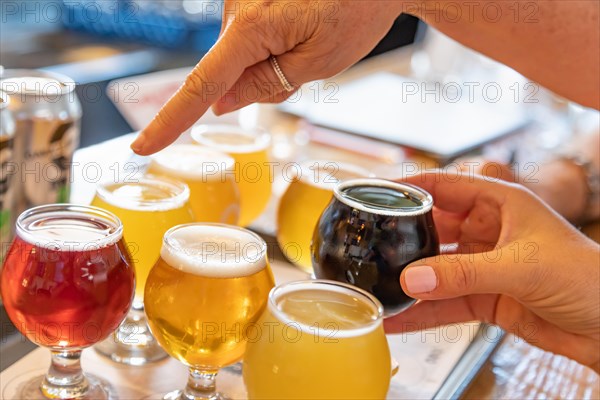 Female hand picking up glass of micro brew beer from variety on tray