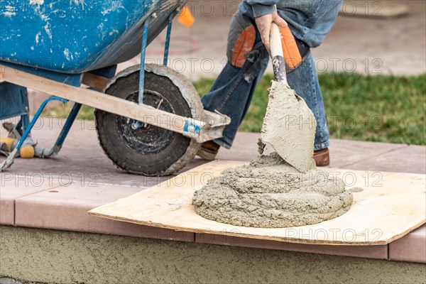 Construction worker placing wet cement on board at pool construction site